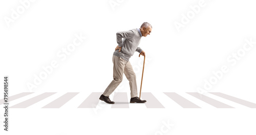 Full length profile shot of an elderly man walking with a bent back at a pedestrian crossing