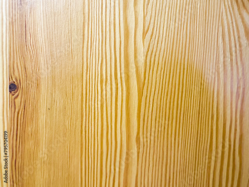 Close-up of a smooth yellow piece of wood with a small round knot in the center. The wood grain is visible and there are minor imperfections on the surface such as small scratches or dents