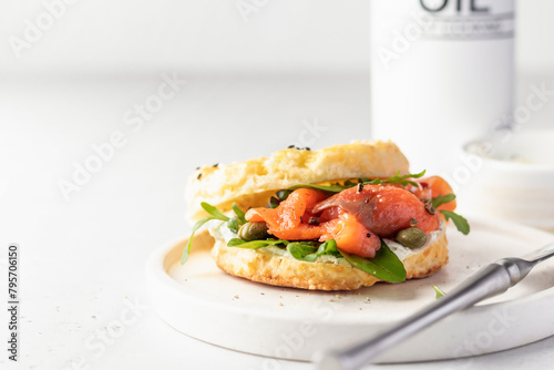Homemade bagel sandwich with smoked salmon, cream cheese, capers and spinach for healthy breakfast on white kitchen background, text space