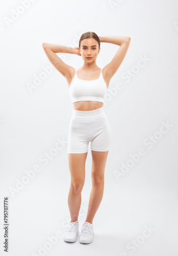 Beautiful attractive girl in white shorts and a top on a white background. The concept of sports and healthy lifestyle.