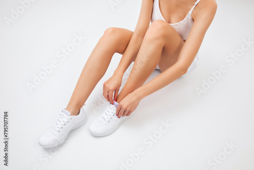 Beautiful attractive girl in white shorts and a top on a white background. The concept of sports and healthy lifestyle.