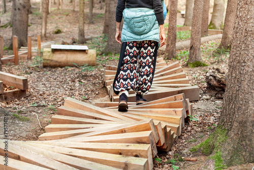 Frau läuft auf Holzstamm im Wald. Motorisches Bewegungskonzept in der Natur. Gleichgewichtsübung auf Holzstämmen. Woman walks on logs in the forest. Balance exercise on logs. 