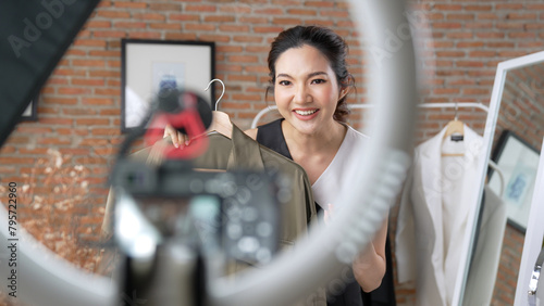 Woman influencer shoot live streaming vlog video review clothes social media or blog. Happy young girl with apparel vivancy studio lighting for marketing recording session broadcasting online.