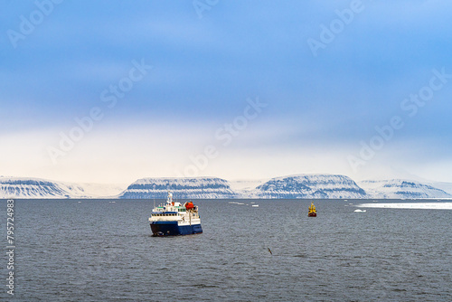 2022-05-09 TWO BOATS IN THE ARCTIC OCEAN WITH SNOW COVERED MOUNTIANS IN THE DISTANCE WITH A LIGHT BLUE SKY NEAR LONGYEARBYEN IN SVALBARG NORWAY