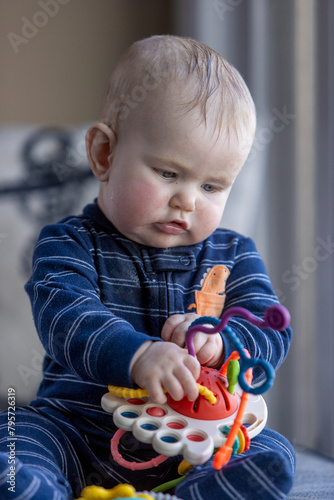 Six month old child holding a toy in his lap