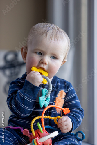 Six month old child putting toy in his mouth.