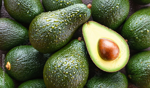 Close-Up of whole ripe green avocados placed together as background, half avocado in center