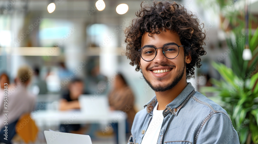 happy young man entrepreneur, with curly hair and glasses in a casual outfit standing at an office happy young man entrepreneur, with curly hair and glasses in a casual outfit standing at an office
