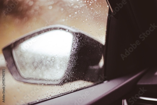 Raindrops falling on the car windscreen with bad visibility on side mirrors car