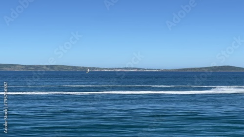 Praia com agua e céu azul, passando uma moto aquática photo