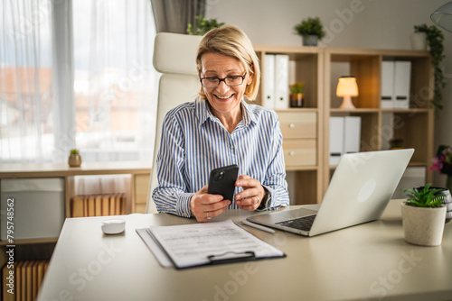 Mature woman with eyeglasses use mobile phone at work