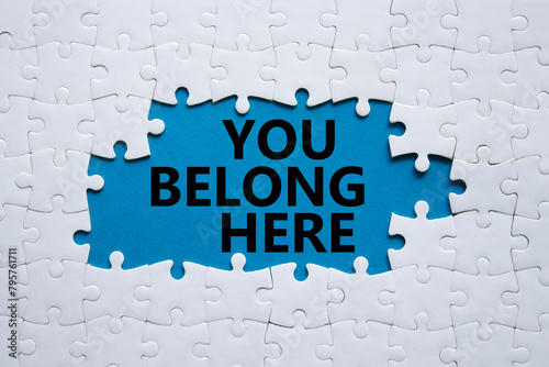 You belong here symbol. White puzzle with words You belong here. Beautiful blue background. Business and You belong here concept. Copy space.