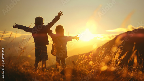 silhouette of children with their hands up in the field at sunset