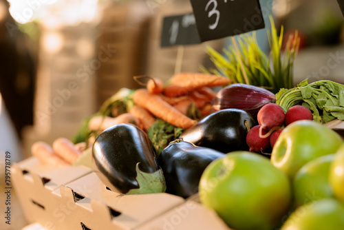 Freshly harvested carrots, eggplants, apples and radish displayed on farmers market stand. Close up of locally grown bio vegetables in cardboard boxes at eco friendly farm produce stand.