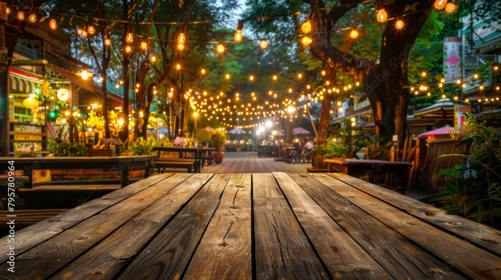 Empty wooden table set against a lively outdoor marketplace lit up by cozy string lights Empty wooden table set against a lively outdoor marketplace lit up by cozy string lights