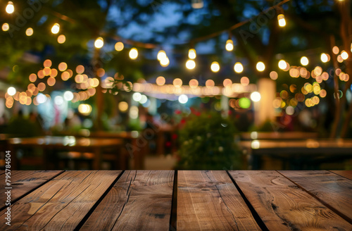 Empty wooden table with defocused lights of an outdoor party ambiance