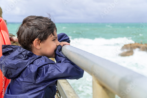 Contemplative child gazing at sea from French pier photo