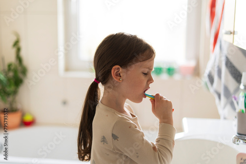 Little girl brushing her teeth in the bathroom. Healthy teeth concept.