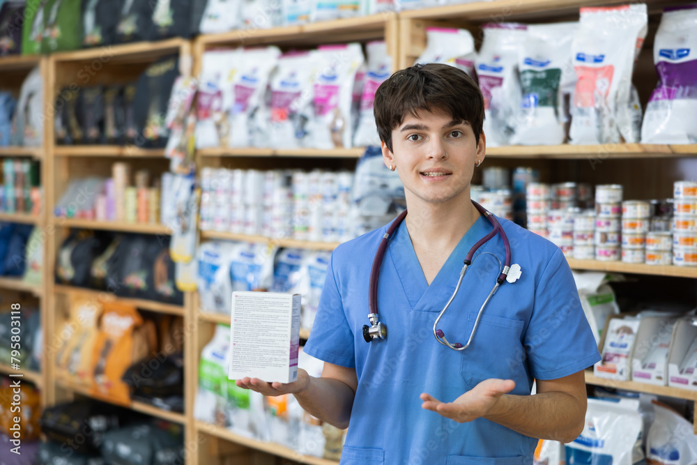 Experienced veterinarian young man is standing in pet store with pack of food in hands. Specialist offers services selection of medical and dietary nutrition for pet