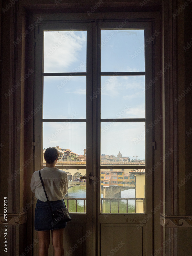 A tourist looks at Ponte Vecchio from inside the Uffizi Galleries, Florence A tourist looks at Ponte Vecchio from inside the Uffizi Galleries, Florence