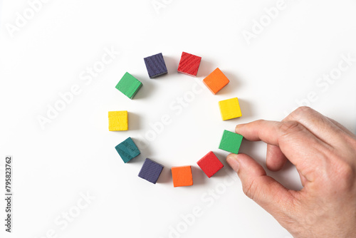 Circle of colorful wooden blocks representing unity of diverse elements or people. © Kenishirotie