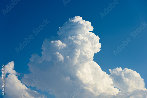 Cumulus white clouds bodies towering in clear blue sky background.