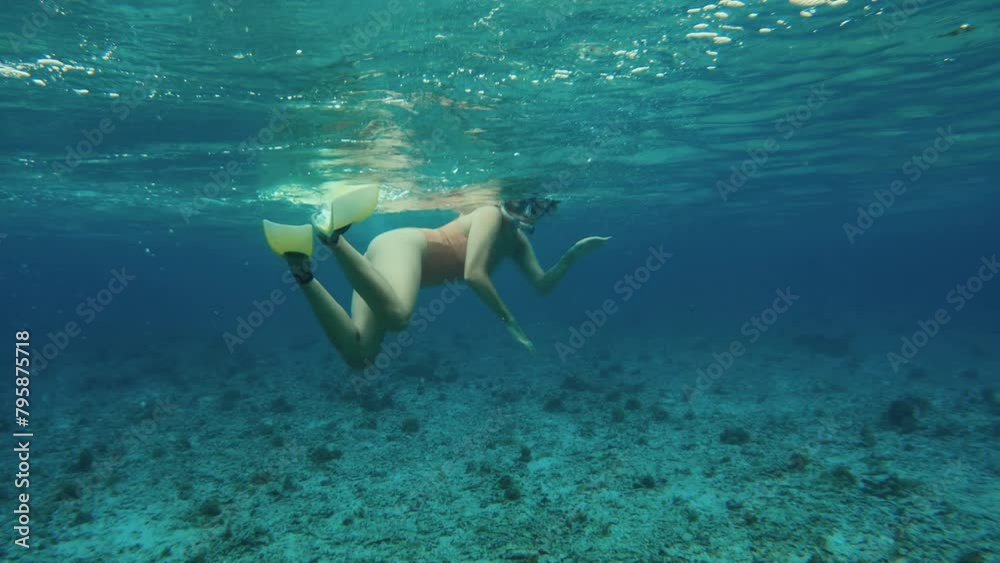 Woman wearing nude beige color swimsuit snorkeling in tropical ocean. Female person free diving in blue sea. Happy vacation. Adventure exploring reef bottom of tropical island. Recreation in summer. 