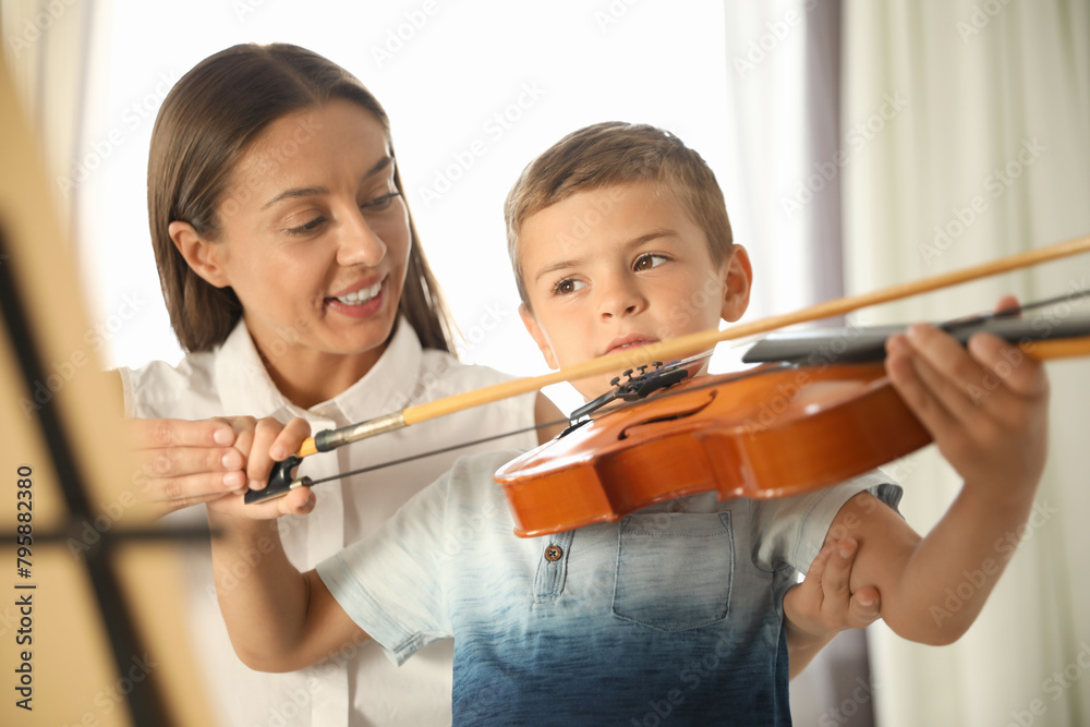 Young woman teaching little boy to play violin indoors Young woman teaching little boy to play violin indoors