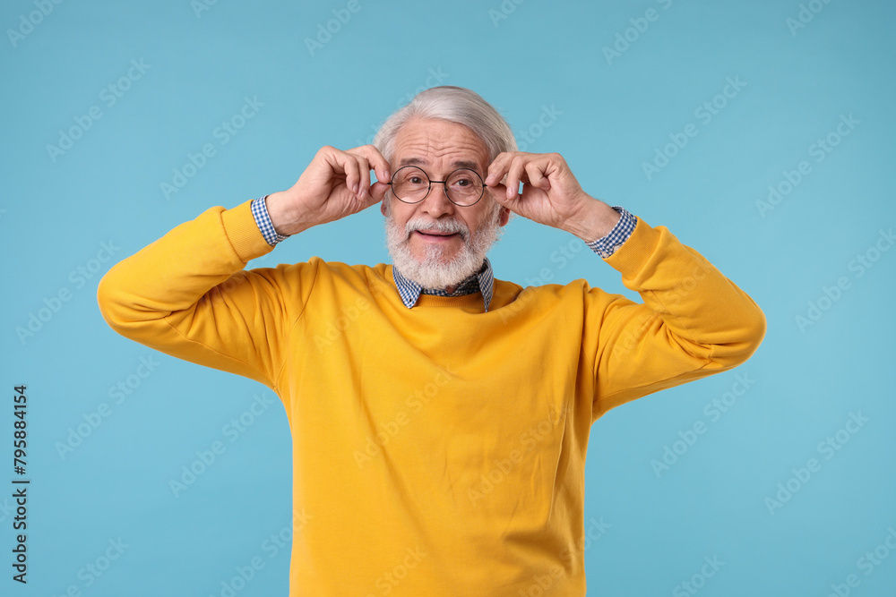 Naklejka premium Portrait of stylish grandpa with glasses on light blue background