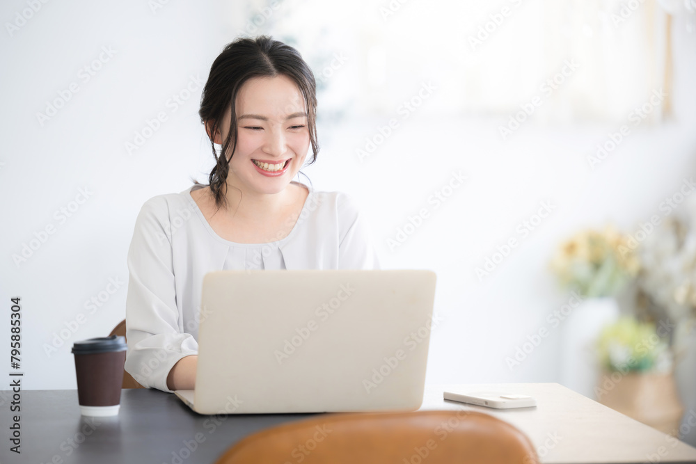 ナチュラルテイストなオフィスでパソコンを操作する若い女性 画面を見てタイピングをする ナチュラルテイストなオフィスでパソコンを操作する若い女性 画面を見てタイピングをする
