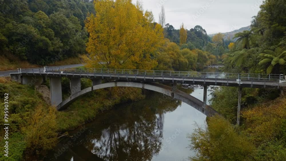 Aerial: Bridge over the Mangawhereo River. The trees are yellow in the Autumn. Kakatahi, whanganui, manawatu, New Zealand. Aerial: Bridge over the Mangawhereo River. The trees are yellow in the Autumn. Kakatahi, whanganui, manawatu, New Zealand.