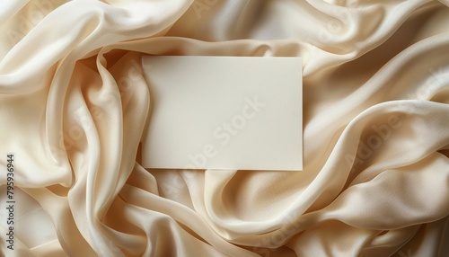 A blank note card sits on a bed of beige silk. photo
