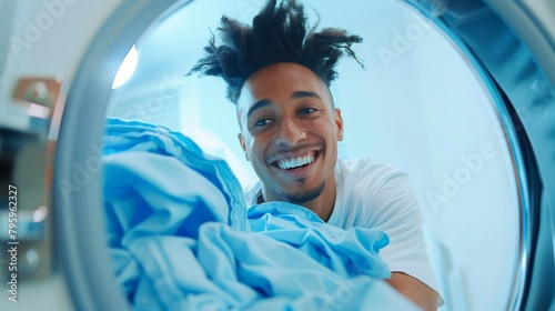 A person with a satisfied smile pulling out clean and fresh laundry from a washing machine in a white room. photo