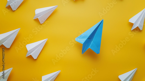 Blue Paper Plane Standing Out in a Group of White Ones on Yellow