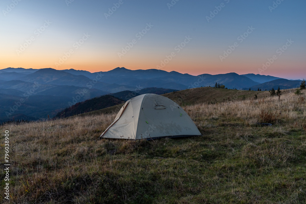 Tourist tent in the mountains. Sunrise in the mountains. Tourist camp and sunrise. Outdoors.