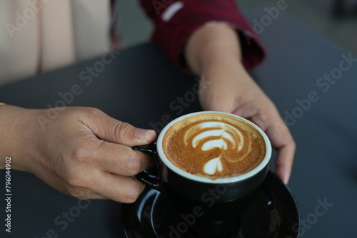 Woman's hand holding a cup of latte coffee