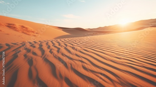 A desert landscape with a sun setting in the background. The sand is dry and the sky is clear