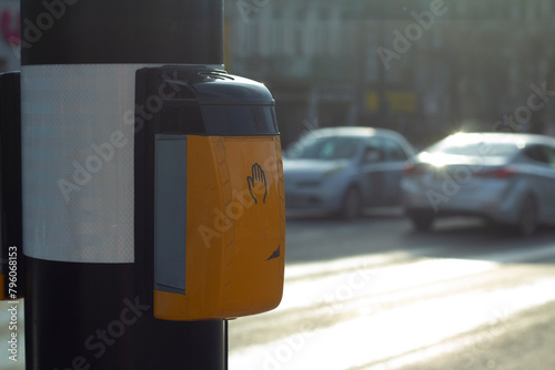 Street photo. Yellow device for switching traffic light signal on pole in front of pedestrian crossing. Car is out of focus. Horizontal banner with copy space for text. Concept of transport, movement