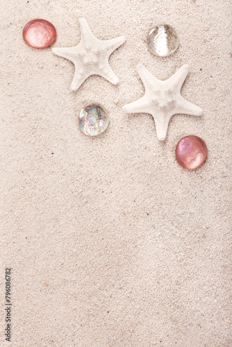 Border with star fish and red pebbles on white sand.