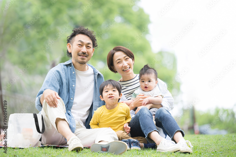 メインビジュアルにも！公園でピクニックをする家族 春夏のお出かけやレジャーのイメージ4人家族　カメラ目線