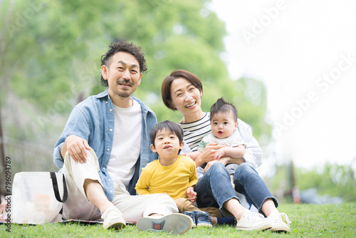 メインビジュアルにも！公園でピクニックをする家族 春夏のお出かけやレジャーのイメージ4人家族　カメラ目線 © kapinon
