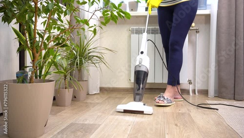 A woman vacuums the floor during home cleaning. House cleaning. Suitable for content about housekeeping. photo