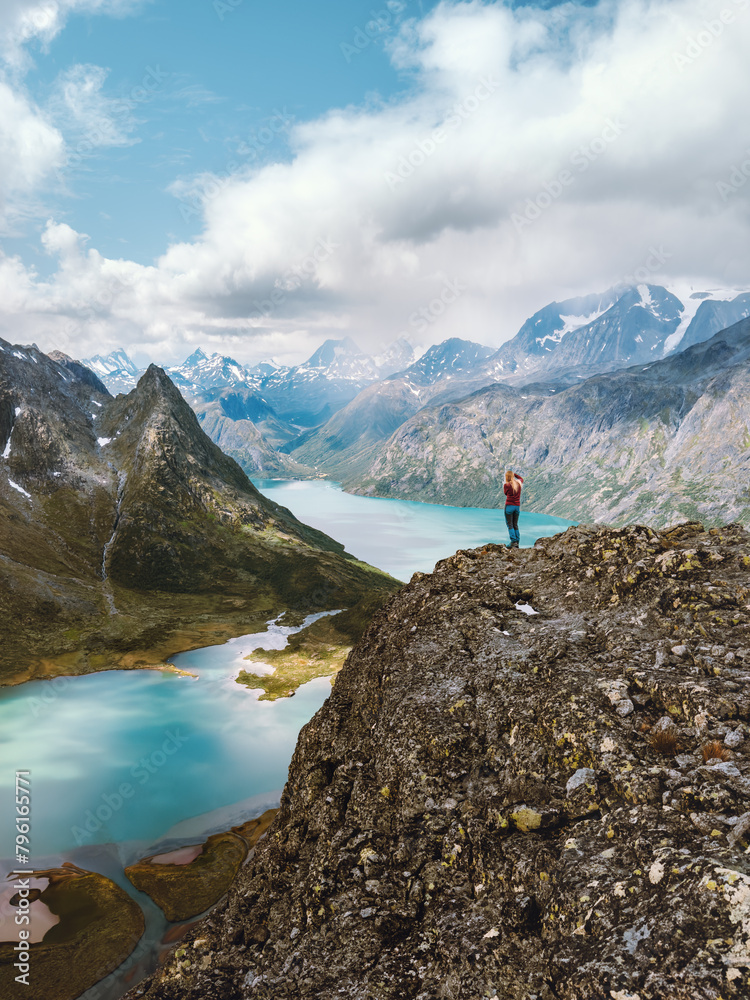 Traveler hiking in Norway travel outdoor active summer vacations, mountains and lakes landscape in Jotunheimen park, woman standing on cliff alone healthy lifestyle adventure trip