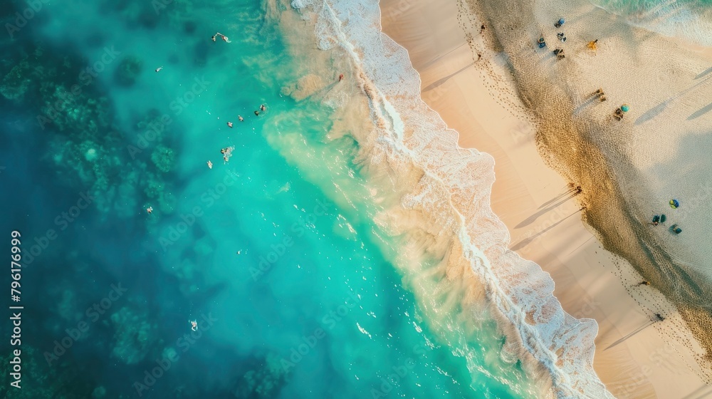Aerial view of a sandy beach with turquoise water and people.