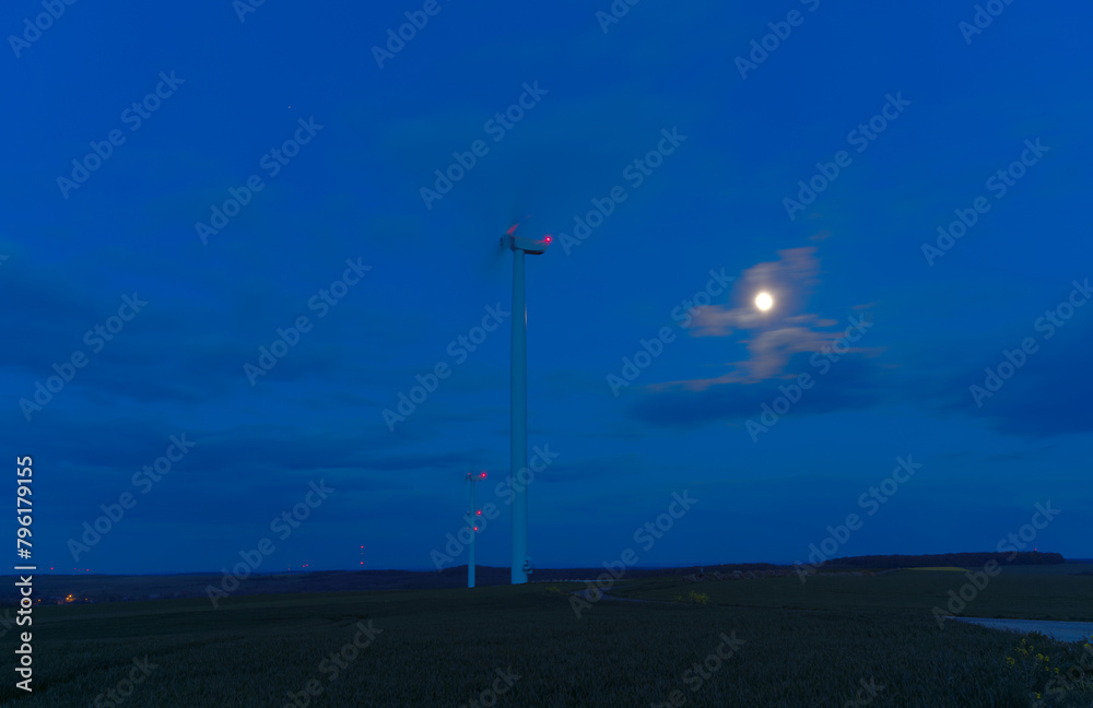 Obraz premium Eolienne de nuit devant la lune