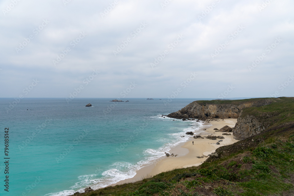 Plage de sable vaste, cernée par hautes falaises bretonnes. Eaux turquoises sous ciel couvert, scène naturelle saisissante. Plage de sable vaste, cernée par hautes falaises bretonnes. Eaux turquoises sous ciel couvert, scène naturelle saisissante.