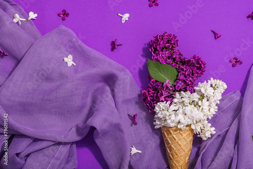 White and violet lilac flowers in waffle ice cream cones on purple background. Flat lay photo