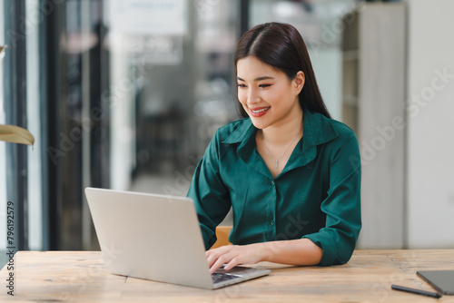 Confident young asian business woman using laptop at modern office.