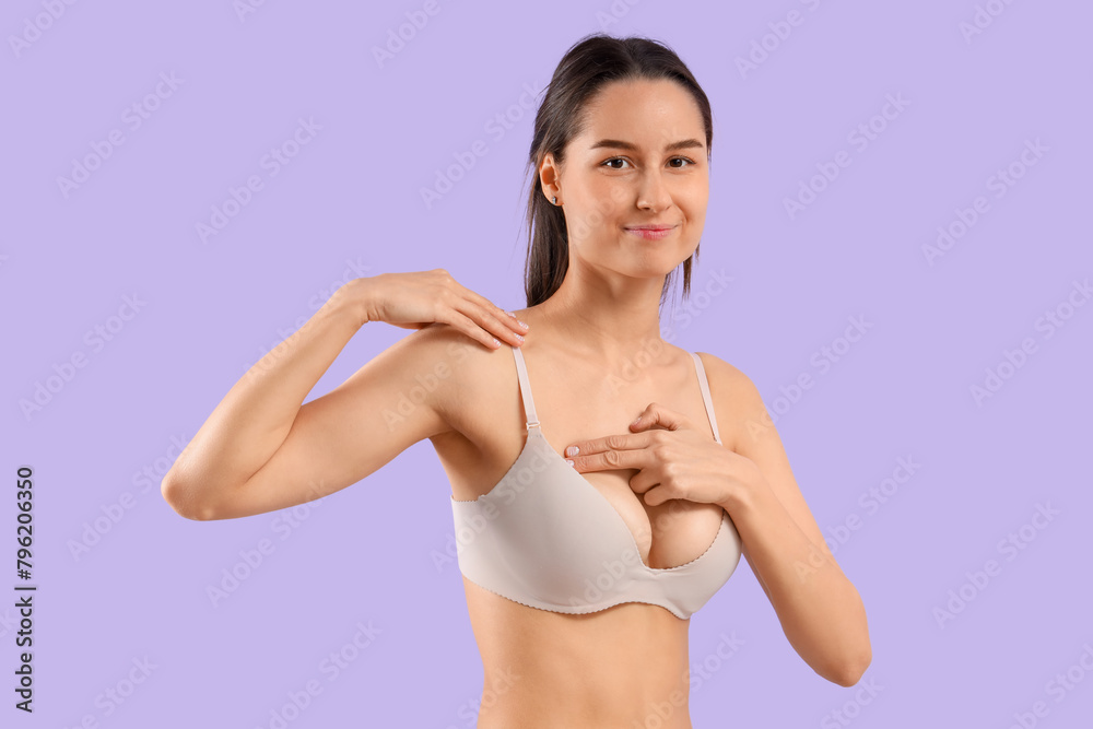 Young woman checking her breast on lilac background. Cancer awareness concept Young woman checking her breast on lilac background. Cancer awareness concept