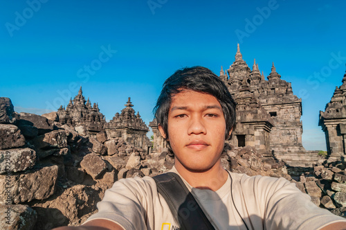 Asian men are taking selfies with the Plaosan temple in the background in the morning. Plaosan Temple was built in the middle of the 9th century by Sri Kahulunnan daughter of Samaratungga. photo